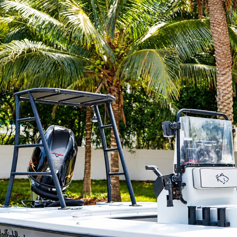 The poling platform rising above the outboard, with the center console and its clear windshield in front, under palm trees