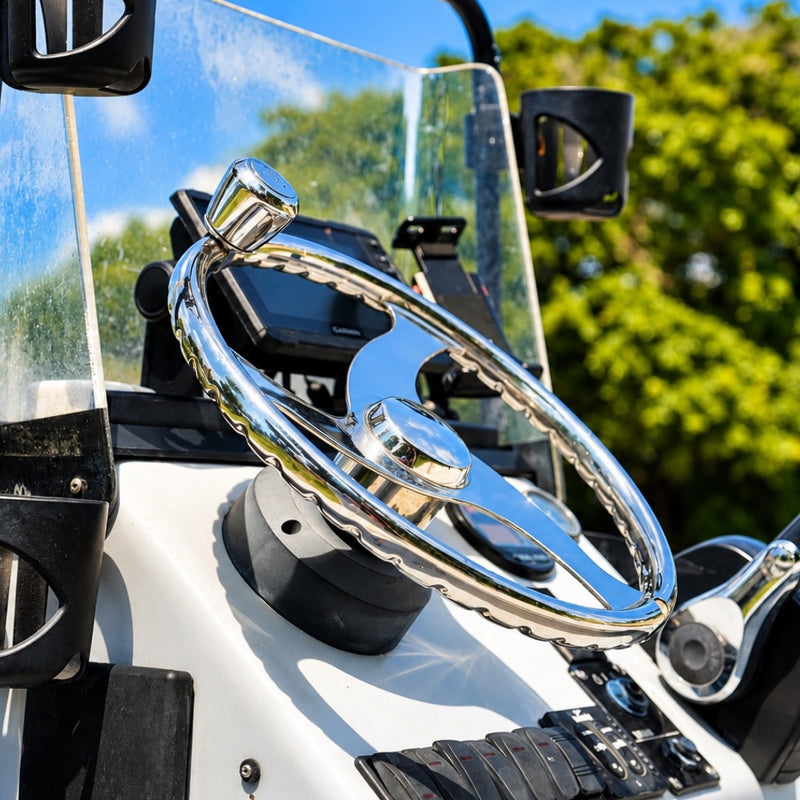 A close view of the stainless steering wheel and windshield at the Redfish console, with green trees blurred behind