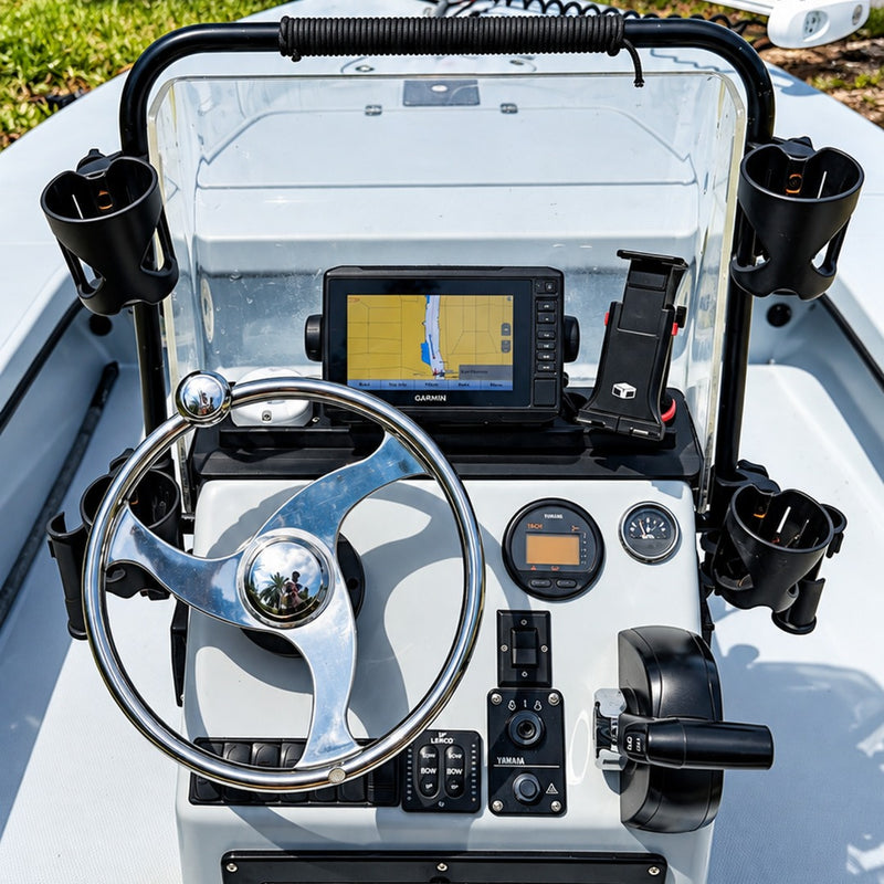 The helm of the boat, with a Garmin screen showing a chart, a stainless steering wheel, gauges and a row of switches