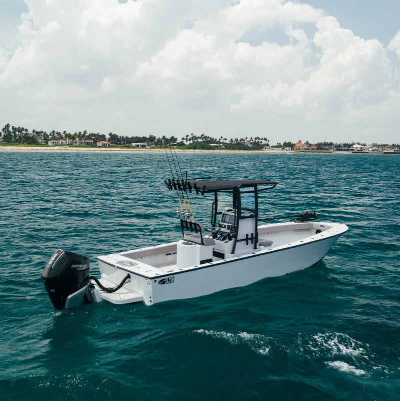 The LTB 25 at rest on the water with its black Mercury outboard tilted up and rods in the T-top