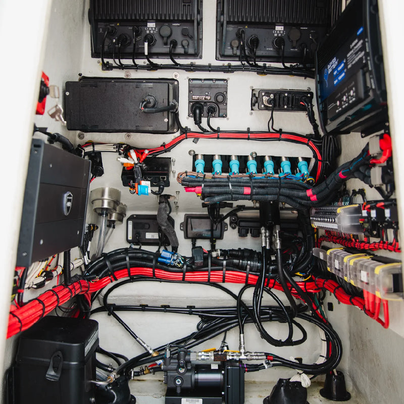 A packed compartment of red and black cables, connectors and electronic modules