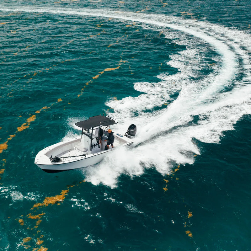 An aerial view of the boat turning hard and throwing a long arc of white spray