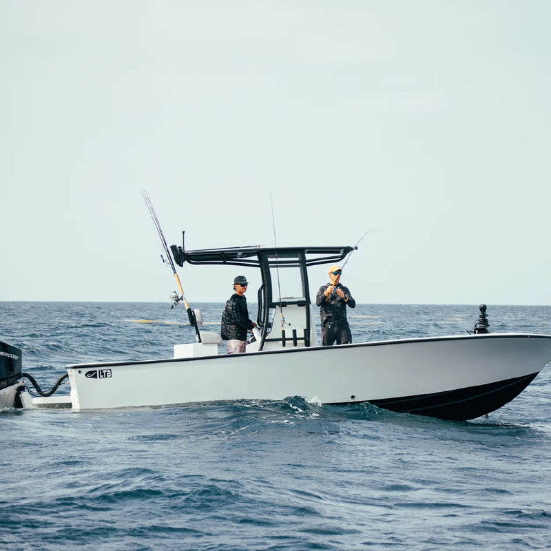 Two people at the console of the LTB 25 on choppy blue water, a rod in hand