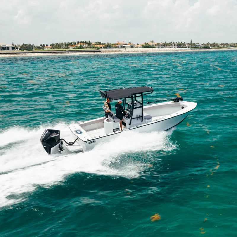 Two people under the T-top as the boat crosses bright turquoise water near the shore
